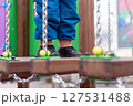Child walking on playground bridge with chains and colorful wooden elements. 127531488