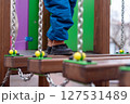 Child walking on playground bridge with chains and colorful wooden elements. 127531489