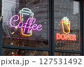 Neon lights featuring coffee, doner kebab, and cup symbols displayed on a glass storefront. These bright signs promote beverages and food, creating a vibrant and welcoming atmosphere for customers. 127531492