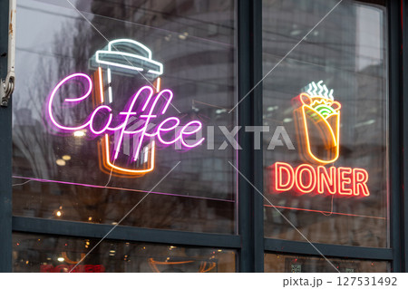 Neon lights featuring coffee, doner kebab, and cup symbols displayed on a glass storefront. These bright signs promote beverages and food, creating a vibrant and welcoming atmosphere for customers. Neon lights featuring coffee, doner kebab, and cup symbols displayed on a glass storefront. These bright signs promote beverages and food, creating a vibrant and welcoming atmosphere for customers. 127531492