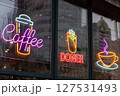 Neon lights featuring coffee, doner kebab, and cup symbols displayed on a glass storefront. These bright signs promote beverages and food, creating a vibrant and welcoming atmosphere for customers. 127531493