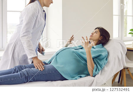 Young pregnant woman lying on the couch visiting gynecologist doctor in hospital or medical clinic. 127532491