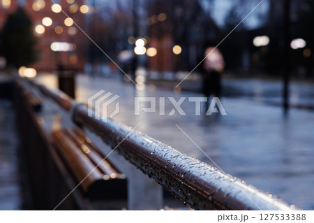 Raindrops glisten on a railing as evening approaches in a bustling urban setting Raindrops glisten on a railing as evening approaches in a bustling urban setting 127533388
