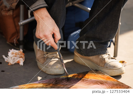 Creative artist immersed in vibrant painting at outdoor art fair on a sunny afternoon 127533404