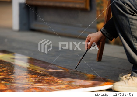 Urban artist creating a vibrant masterpiece on the sidewalk during a sunny afternoon in a bustling city 127533408