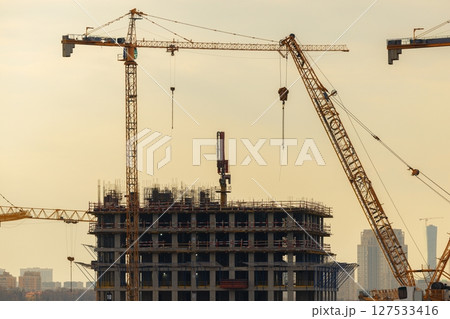 Modern construction site showcases cranes at work during golden hour in an urban landscape Modern construction site showcases cranes at work during golden hour in an urban landscape 127533416