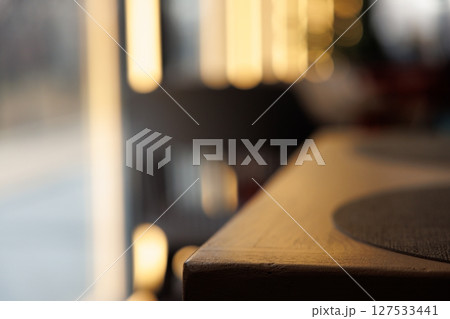 Warm sunlight dapples a wooden table in an inviting cafe atmosphere during the late afternoon hours 127533441