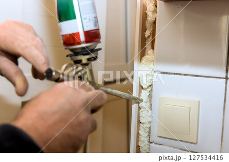 Hands applying foam sealant in home improvement project during works day Hands applying foam sealant in home improvement project during works day 127534416