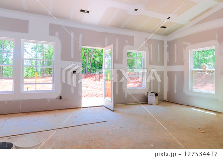 Interior of new home under construction with drywall installed an open door leading outside 127534417