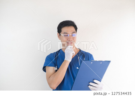 Thoughtful Male Nurse in Scrubs Reviewing Medical Chart Thoughtful Male Nurse in Scrubs Reviewing Medical Chart 127534435