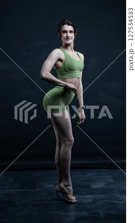 Confident fitness model posing on black background showing muscles Confident fitness model posing on black background showing muscles 127534583