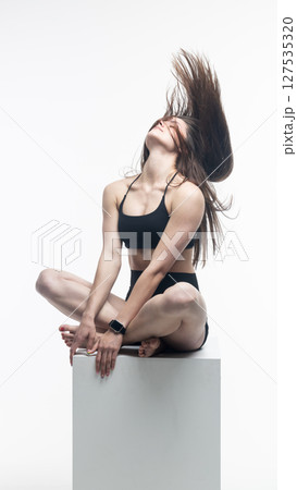 Young athletic woman posing on white cube in studio Young athletic woman posing on white cube in studio 127535320