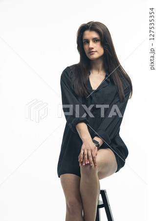 Young woman sitting on stool wearing transparent heels and smartwatch Young woman sitting on stool wearing transparent heels and smartwatch 127535354