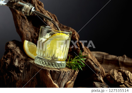 Cocktail gin and tonic with lemon slices and sprig of rosemary. 127535514