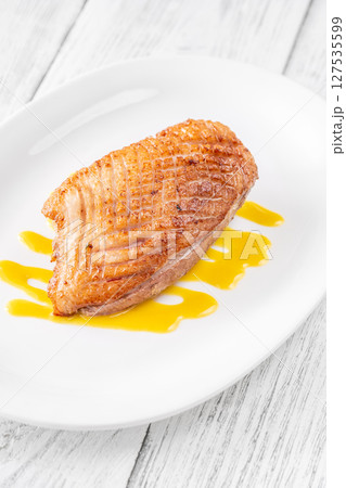 Whole Crispy Duck Breast on Mustard Lemon Honey Sauce in White Plate 127535599