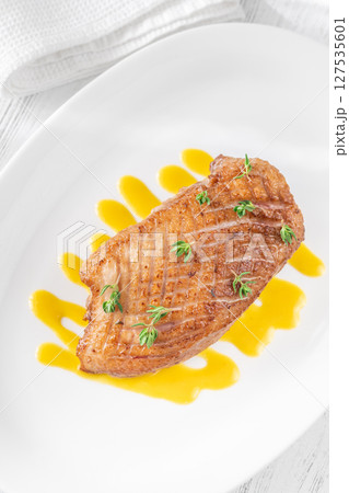 Whole Crispy Duck Breast on Mustard Lemon Honey Sauce in White Plate 127535601