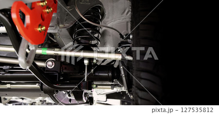 Car suspension part. Close up of a rear car suspension and exhaust system. such as coil springs link arms axle housing and performance exhaust. For auto engineering or car suspension part industry use 127535812