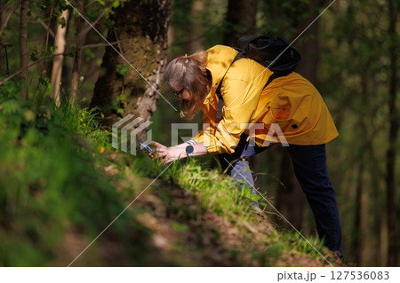Exploring nature with curiosity in a vibrant yellow raincoat during a sunny day in the forest Exploring nature with curiosity in a vibrant yellow raincoat during a sunny day in the forest 127536083