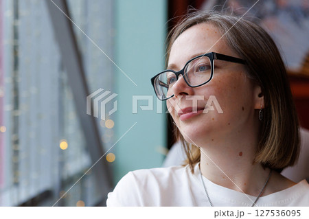 Woman enjoying a quiet moment by the window in a cozy urban cafe on a sunny day Woman enjoying a quiet moment by the window in a cozy urban cafe on a sunny day 127536095