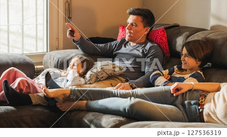 Family relaxing on sofa watching television together 127536319