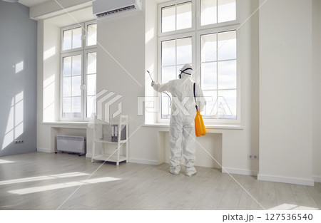 Pest control exterminator in protective suit spraying insecticide over windows in the house Pest control exterminator in protective suit spraying insecticide over windows in the house 127536540