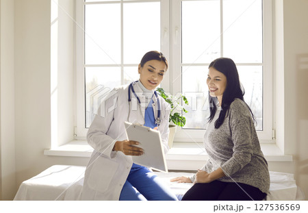 Doctor showing report file with appointment and giving consultation to a woman patient. 127536569