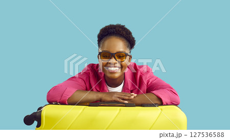 Young african woman isolated on blue wall studio mid aged style traveler holds on suitcase. 127536588