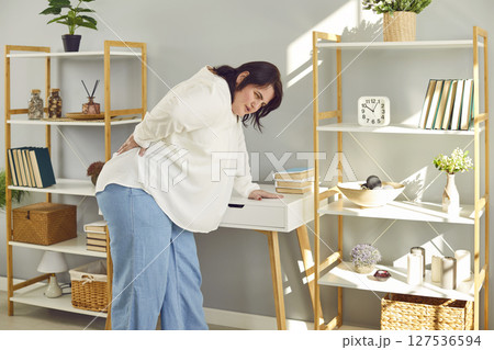 Overweight young woman suffering from backache touching her lower back 127536594