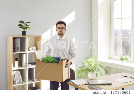 Young male office worker who quits or gets fired packs his stuff and leaves the workplace Young male office worker who quits or gets fired packs his stuff and leaves the workplace 127536601
