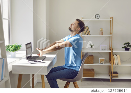 Relaxed tired business man resting and stretching arms at the desk relaxing at office. Relaxed tired business man resting and stretching arms at the desk relaxing at office. 127536614