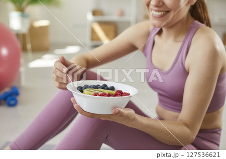 Sporty young girl in sportswear eating healthy food after working out at home. Sporty young girl in sportswear eating healthy food after working out at home. 127536621