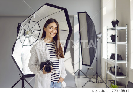 Young female photographer with digital camera posing in photo studio Young female photographer with digital camera posing in photo studio 127536651