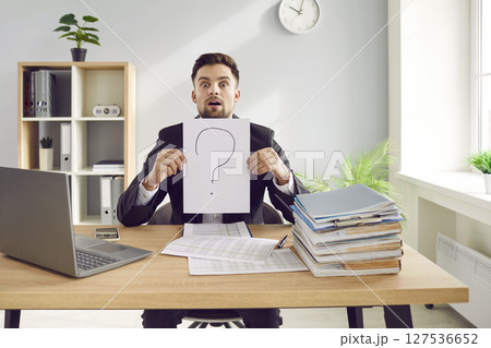 Funny male office worker is confused and has lots of questions at work in office 127536652