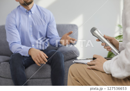 Closed up of woman with microphone interviewing businessman in office 127536653