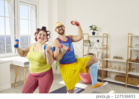 Funny overweight fat woman with bearded man in bright sportswear doing exercises at home together. 127536655