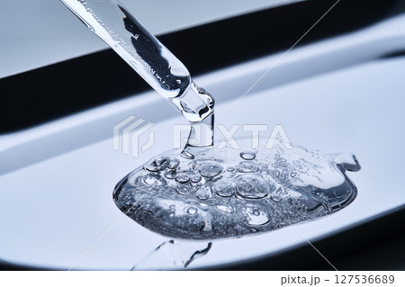 The texture of cosmetic serum in a pipette on a blue background. 127536689