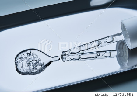 The texture of serum with spicules in a dropper on a blue background. The texture of serum with spicules in a dropper on a blue background. 127536692