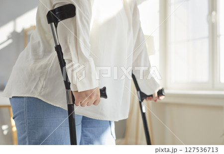Cropped photo of a handicapped overweight fat woman with crutches trying to walk at home. Cropped photo of a handicapped overweight fat woman with crutches trying to walk at home. 127536713