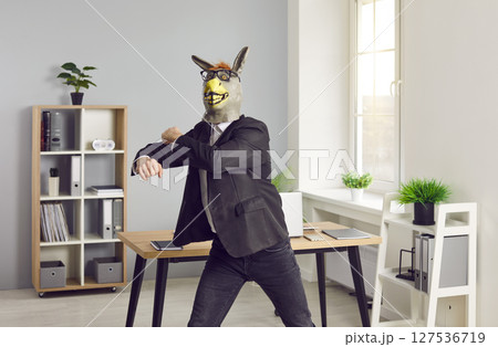 Happy office worker in donkey mask has fun at end of work day, wants to party and dances Happy office worker in donkey mask has fun at end of work day, wants to party and dances 127536719