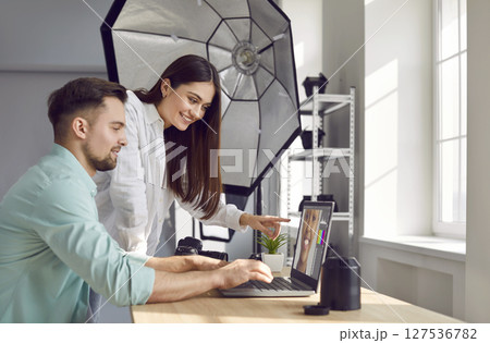 Male photographer and female model choosing photos on laptop together Male photographer and female model choosing photos on laptop together 127536782