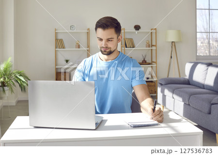 Young business man working at home or at office on a laptop computer sitting at the desk. Young business man working at home or at office on a laptop computer sitting at the desk. 127536783
