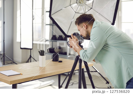 Professional object photographer working in his studio and taking photos of cactus on table 127536820