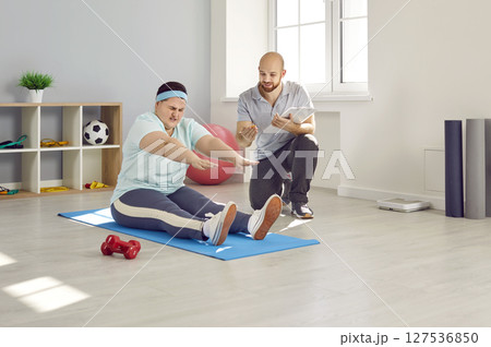 Overweight woman trying to do difficult exercise during workout with personal trainer Overweight woman trying to do difficult exercise during workout with personal trainer 127536850