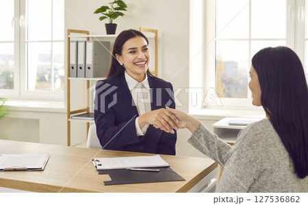 Two smiling businesswomen shaking hands after successful job interview Two smiling businesswomen shaking hands after successful job interview 127536862