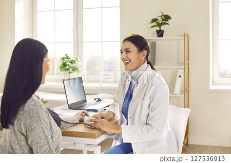 Smiling woman doctor therapist measuring blood pressure of a patient sitting back in the office. Smiling woman doctor therapist measuring blood pressure of a patient sitting back in the office. 127536913