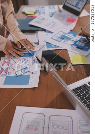 Close up ux developer and ui designer brainstorming about mobile app interface wireframe design on table with customer breif and color code at modern office.Creative digital development agency. Close up ux developer and ui designer brainstorming about mobile app interface wireframe design on table with customer breif and color code at modern office.Creative digital development agency. 127537018