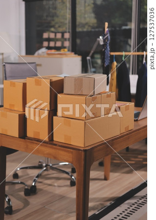 Startup SME small business entrepreneur of freelance Asian woman wearing apron using laptop and box to receive and review orders online to prepare to pack sell to customers, online sme business ideas. 127537036