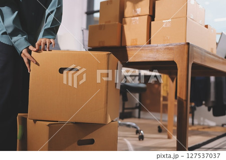 Startup SME small business entrepreneur of freelance Asian woman wearing apron using laptop and box to receive and review orders online to prepare to pack sell to customers, online sme business ideas. 127537037