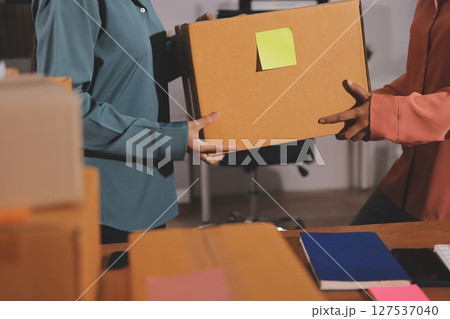 Startup SME small business entrepreneur of freelance Asian woman wearing apron using laptop and box to receive and review orders online to prepare to pack sell to customers, online sme business ideas. 127537040