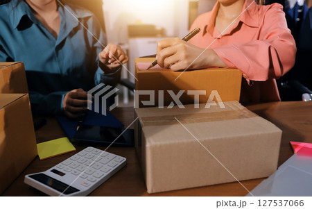 Startup SME small business entrepreneur of freelance Asian woman wearing apron using laptop and box to receive and review orders online to prepare to pack sell to customers, online sme business ideas. 127537066